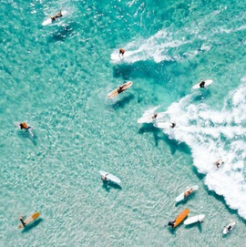 Surfers onboards in the ocean with clear blue water and white waves.