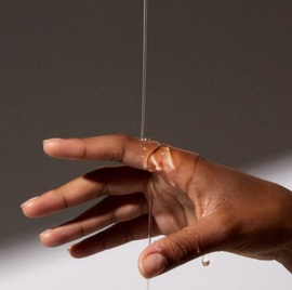 Hand holding a string with a small object hanging from it against a neutral background