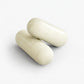Two white digestive enzyme capsules on a light gray background
